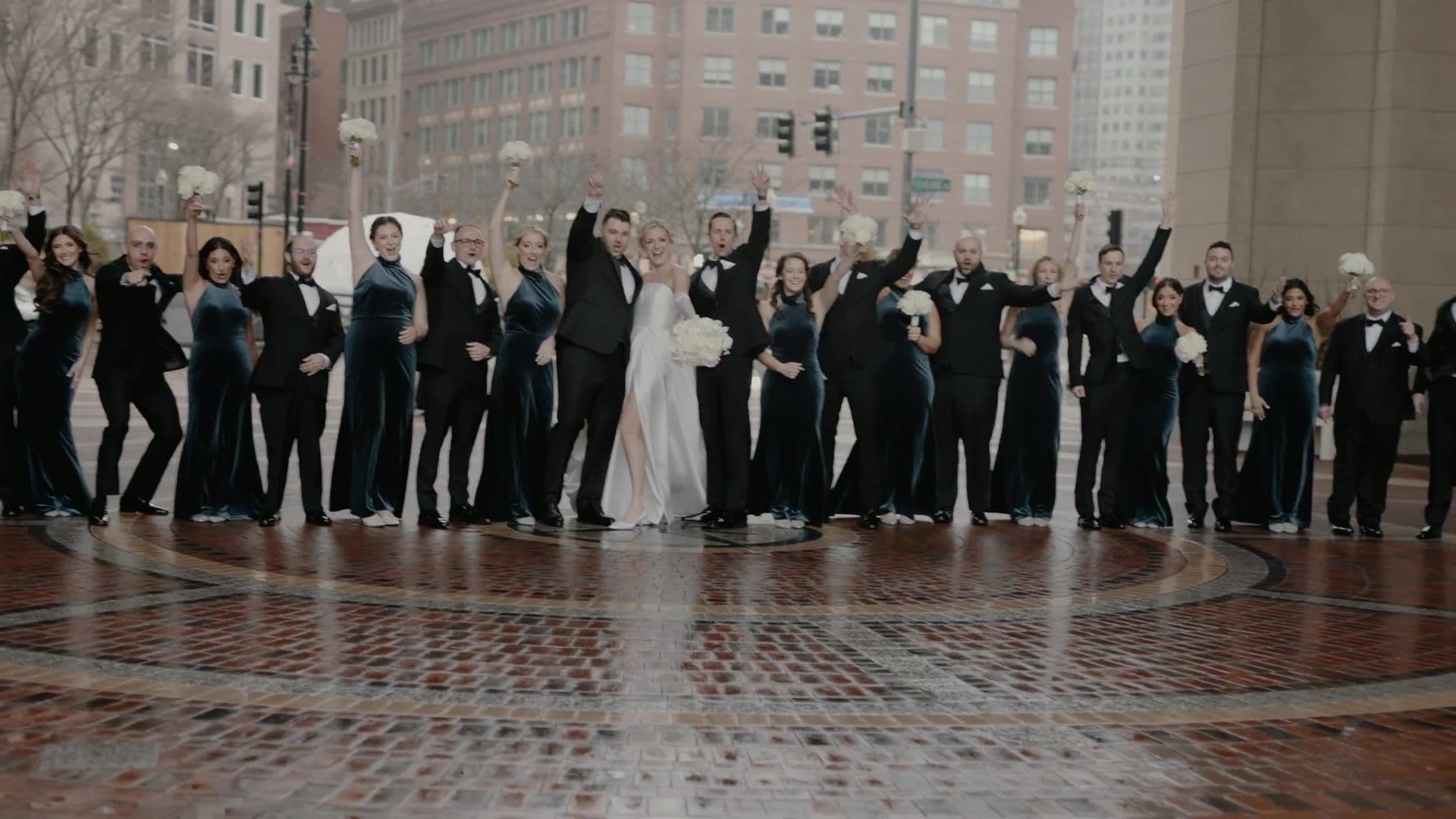 A wedding party jumping together on the brick rotunda plaza at Rowes Wharf, Boston Harbor Hotel