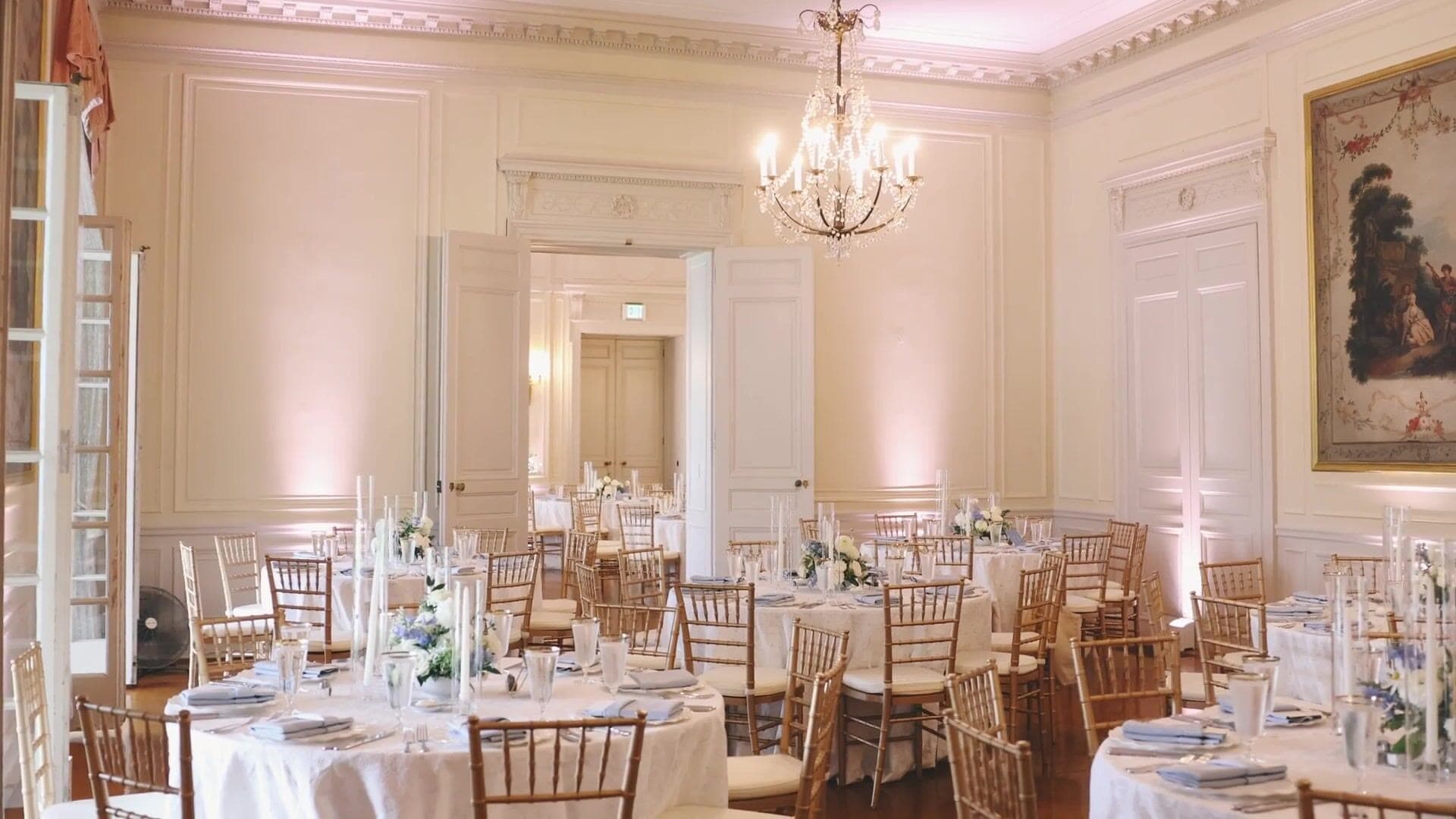 The ballroom at Glen Manor House set for a wedding dinner, with round tables, gold chairs and a chandelier