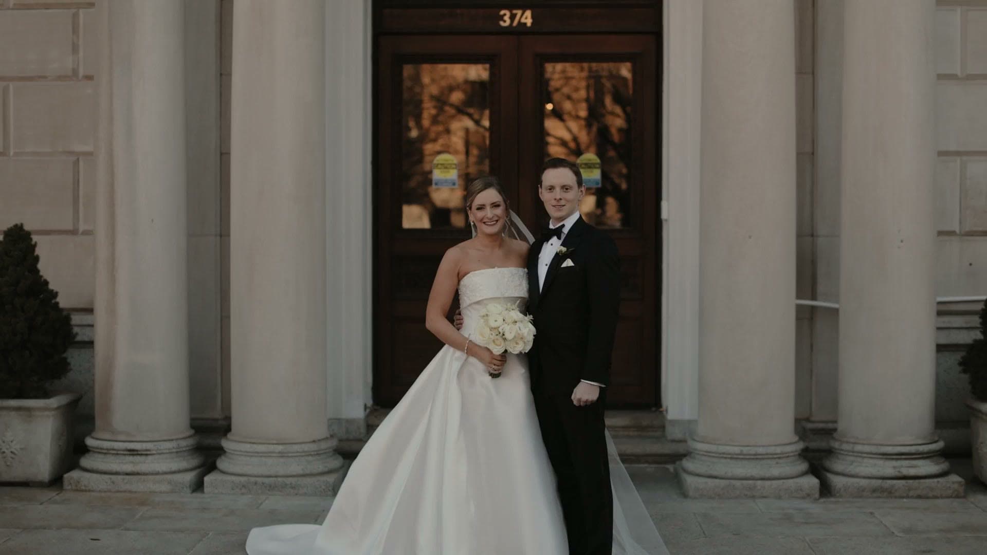 A bride and groom at the front door of the Harvard Club of Boston, between stone columns, with the number 374 above the door