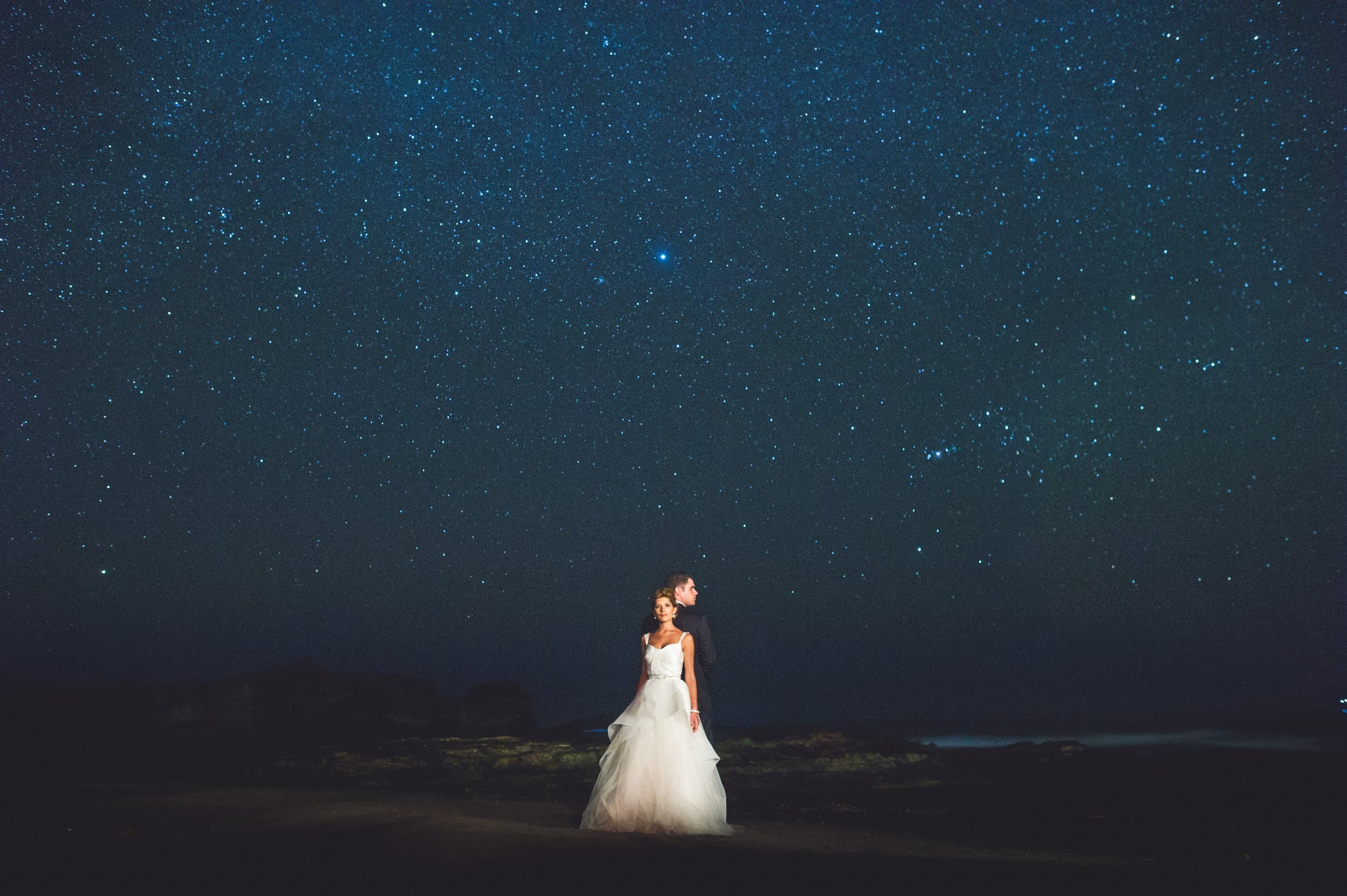 A bride standing beneath a night sky full of stars